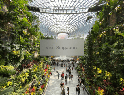 The words “Visit Singapore” in grey on a rectangle over an image of Singapore's Jewel indoor waterfall. The rectangle has a translucent frosted glass effect.